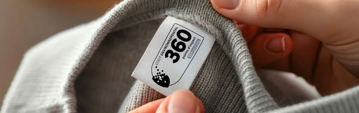 Étiquette affichant le coût environnemental d’un vêtement avec un score de 360 points d’impact, tenue entre deux mains